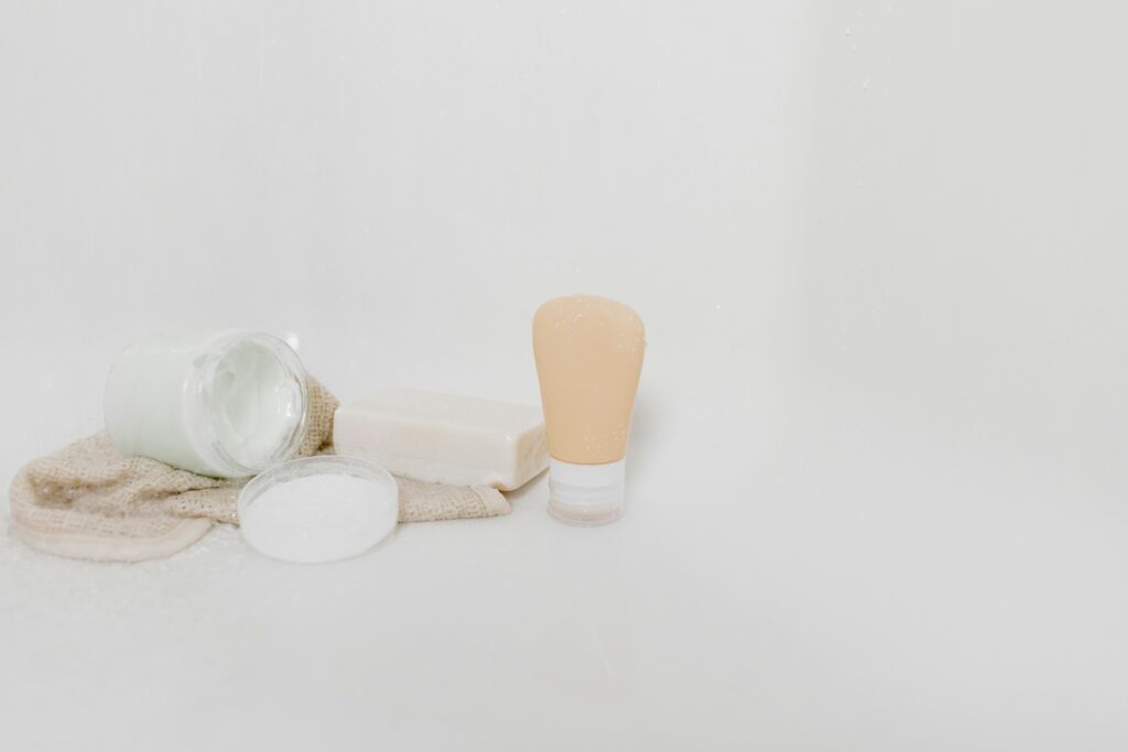 Minimalist setup of skincare products including cream, soap, and lotion on a white surface for beauty and self-care themes.